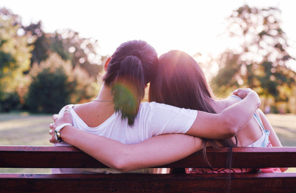 Two people embraced on a park bench.